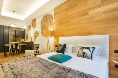 a bedroom with a large white bed with wooden walls at Tivoli Double in Ljubljana