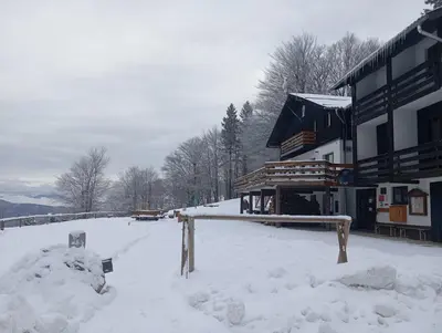a building covered in snow with a pile of snow at Planinski dom Kal in Dol pri Hrastniku