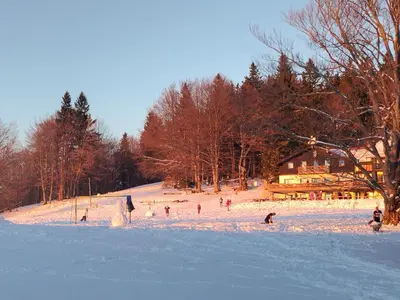 a group of people on a snow covered slope at Planinski dom Kal in Dol pri Hrastniku
