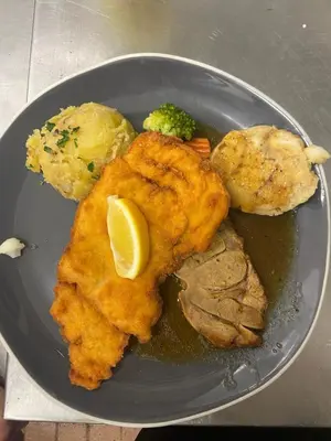 a plate of food with fish and potatoes and a lemon at Planinski dom Kal in Dol pri Hrastniku