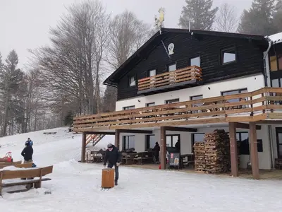 a man standing in the snow in front of a building at Planinski dom Kal in Dol pri Hrastniku