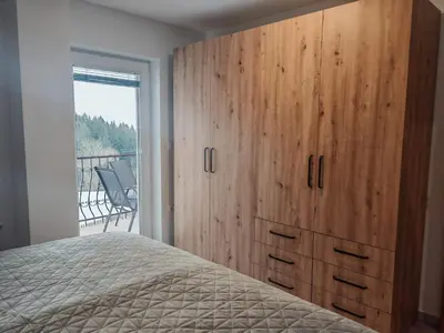 a bedroom with a large wooden cabinet and a bed at Apartma pod Tremi Kralji in Oplotnica