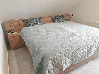 a bedroom with a large bed with a wooden headboard at Apartma pod Tremi Kralji in Oplotnica
