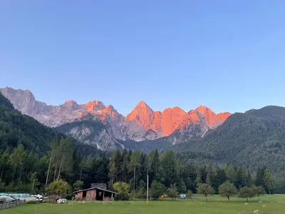 a group of mountains with a green field and a house at Apartment Barbara with sauna in Gozd Martuljek