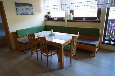 a dining room with a table and chairs and a couch at Apartma jezero MIG in Bohinj