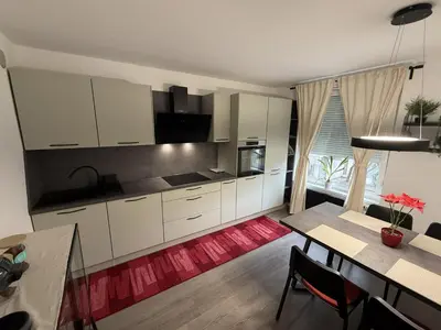 a kitchen with white cabinets and a table and a dining room at Mary's flat in Ljubljana