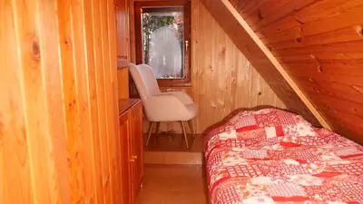 a bedroom with a bed and a chair in a cabin at Holiday cottage Pod Smreko in Cerklje na Gorenjskem