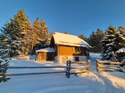 a wooden cabin in the snow with a fence at Holiday cottage Pod Smreko in Cerklje na Gorenjskem
