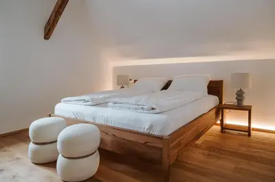 a bedroom with a bed with white sheets and two white chairs at Apartmaji Matec in Fala