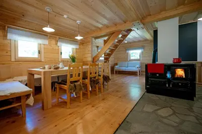 a living room with a dining table and a fireplace at Alpine Loghouse Planšarska bajta Matkov Kot in Solčava