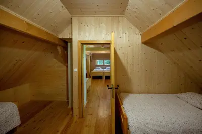 a small room with two beds in a wooden house at Alpine Loghouse Planšarska bajta Matkov Kot in Solčava