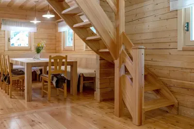 a dining room with a table and a wooden wall at Alpine Loghouse Planšarska bajta Matkov Kot in Solčava