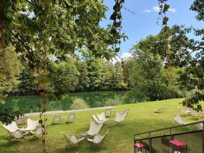 a group of chairs sitting in the grass next to a lake at VRBA Premium riverside mobile house BIG BERRY in Gradac