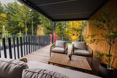 a wooden deck with two chairs and a table at Lanina Chalet Luxury Mountain Escape in Pohorje