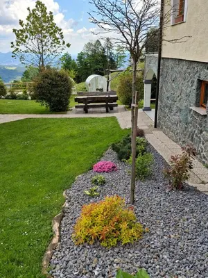 a garden with a bench and a tree in a yard at Apartma Spodnji Goltnik 1 in Mozirje