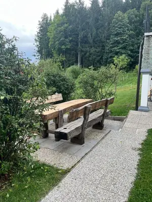 a wooden bench sitting next to a field at Apartma Spodnji Goltnik 1 in Mozirje