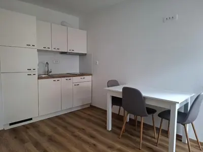 a white kitchen with a white table and chairs at Cosy central apartment in Litija