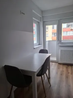 a white table and chairs in a room with windows at Cosy central apartment in Litija