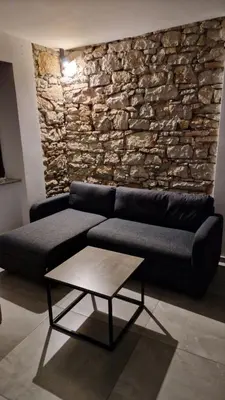a living room with a couch and a stone wall at Mark & Lana in Sežana
