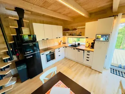 a kitchen with white cabinets and a black refrigerator at Secluded Romantic Cabin · Hot Tub & Barrel Sauna