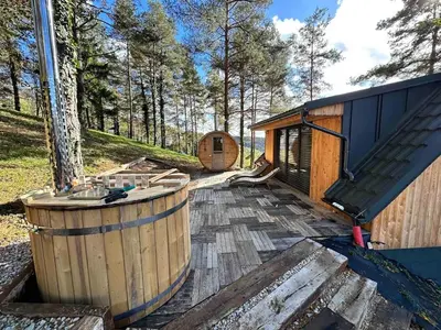 a wooden tub sitting on a deck next to a cabin at Secluded Romantic Cabin · Hot Tub & Barrel Sauna