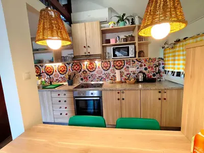 a kitchen with wooden cabinets and green chairs at Boho House 6 camp Terme Catez with promotional tickets prices in Čatež ob Savi