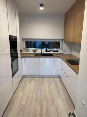 a kitchen with white cabinets and a wooden floor at Cosy house with sauna and jacuzzi in Miklavž na Dravskem Polju
