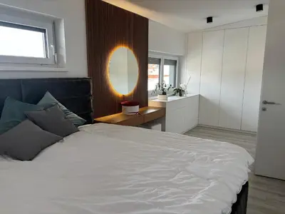 a bedroom with a large white bed and a mirror at Cosy house with sauna and jacuzzi in Miklavž na Dravskem Polju