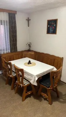 a dining room table with two chairs and a cross on the wall at Apartments Vila Ančka in Tržič