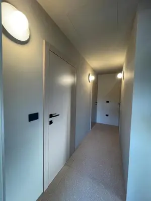 a hallway with white walls and a door and lights at Lanina Estate in Spodnje Hoče