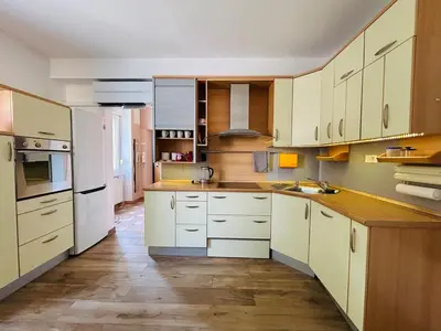 a kitchen with white cabinets and a wooden floor at Spacious & Calm Guesthouse in Ljubljana in Ljubljana
