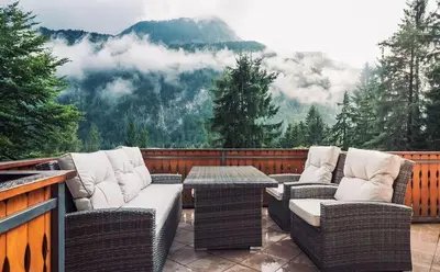 a patio with wicker chairs and a table on a balcony at Mountain View House - Panoramic! in Gozd Martuljek