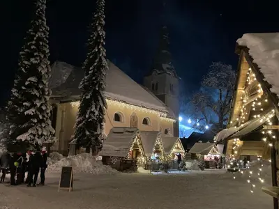 a building with christmas lights in front of a church at Mountain View House - Panoramic! in Gozd Martuljek
