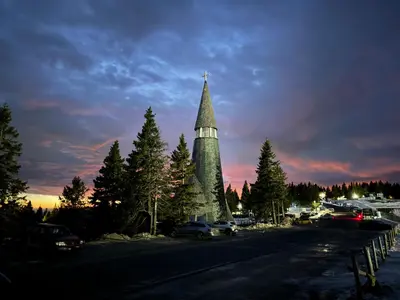 a tall building with a steeple in a parking lot at Rogla Gaber Studio in Zreče