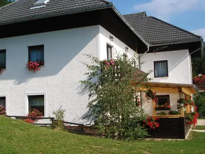 a white house with flowers on the side of it at Farmstay Hiša Pečovnik in Luče