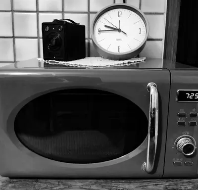 a clock and a camera sitting on top of a microwave at Peace, homeliness and wonderful memories! in Maribor