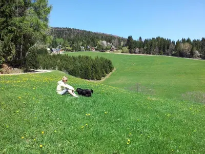 a man sitting in a field with a black dog at Holiday Home Tone in Frajhajm