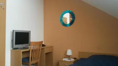 a bedroom with a desk with a television and a mirror at Motel Majolka in Ptuj