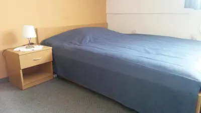 a bedroom with a blue bed and a nightstand with a lamp at Motel Majolka in Ptuj