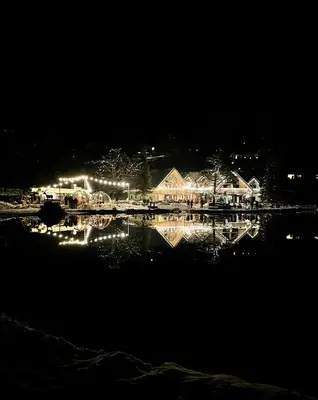a night view of a house with lights in the water at Ian's Residence in Kranjska Gora