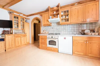a kitchen with wooden cabinets and white appliances at Apartmajska hiša Muštrinka in Cerklje na Gorenjskem