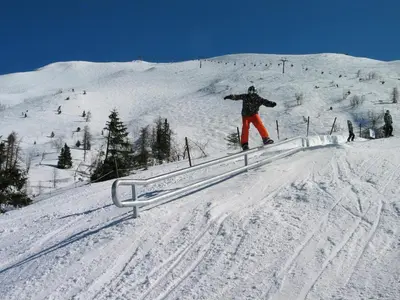 a person riding a snowboard on a rail in the snow at Apartmajska hiša Muštrinka in Cerklje na Gorenjskem