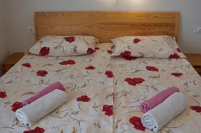a bed with two towels and red flowers on it at Apartmaji JOŠT in Bohinj