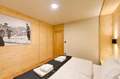 a bedroom with a bed in a wooden wall at Apartments Budinek in Kranjska Gora