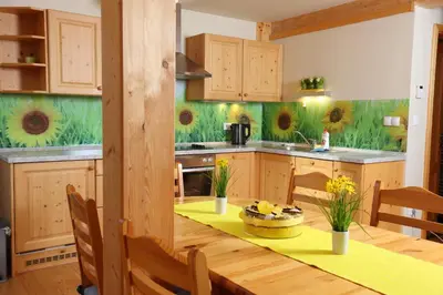 a kitchen with a wooden table with a yellow table cloth at Apartments Budinek in Kranjska Gora