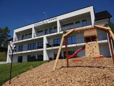 an apartment building with a playground in front of it at Relax Center Olimian in Podčetrtek