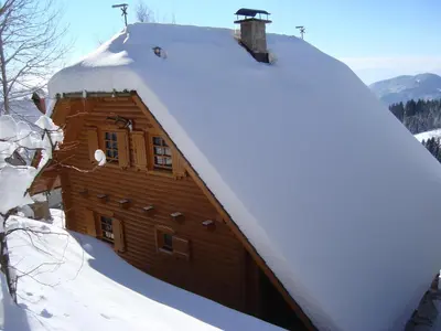 a wooden cabin with a snow covered roof at Charming Chalet Rogla in Hudinja