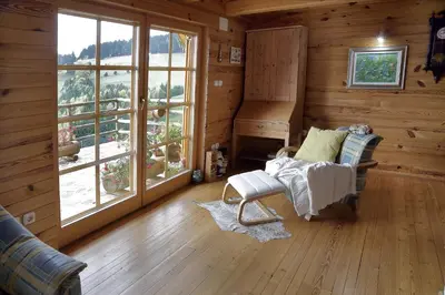 a room with a chair and a piano in a log cabin at Charming Chalet Rogla in Hudinja