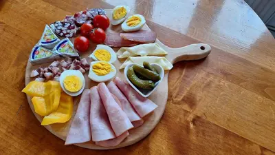 a plate of food with eggs and meats and fruit at Mill House Apartment and Camping in Ljutomer
