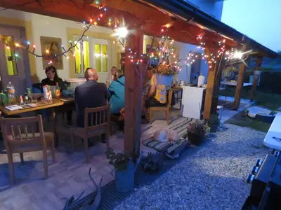 a group of people sitting at a table under a pergola with lights at Mill House Apartment and Camping in Ljutomer